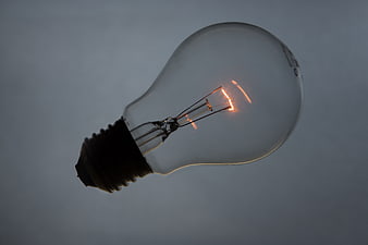 Glowing incandescent light bulb on gray background