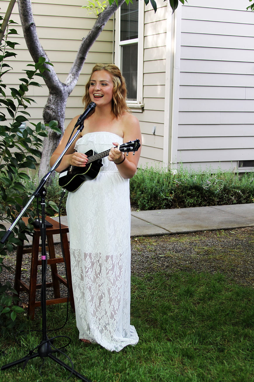 Woman in White Dress Singing and Playing Ukulele Outdoors