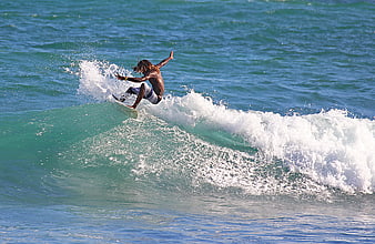 Surfer performing aerial maneuver on turquoise ocean wave