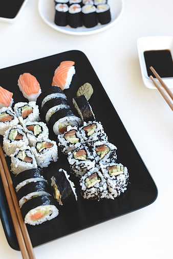 Assorted sushi platter with salmon nigiri and rolls on black tray