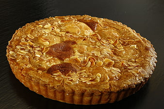 Golden almond tart on dark background