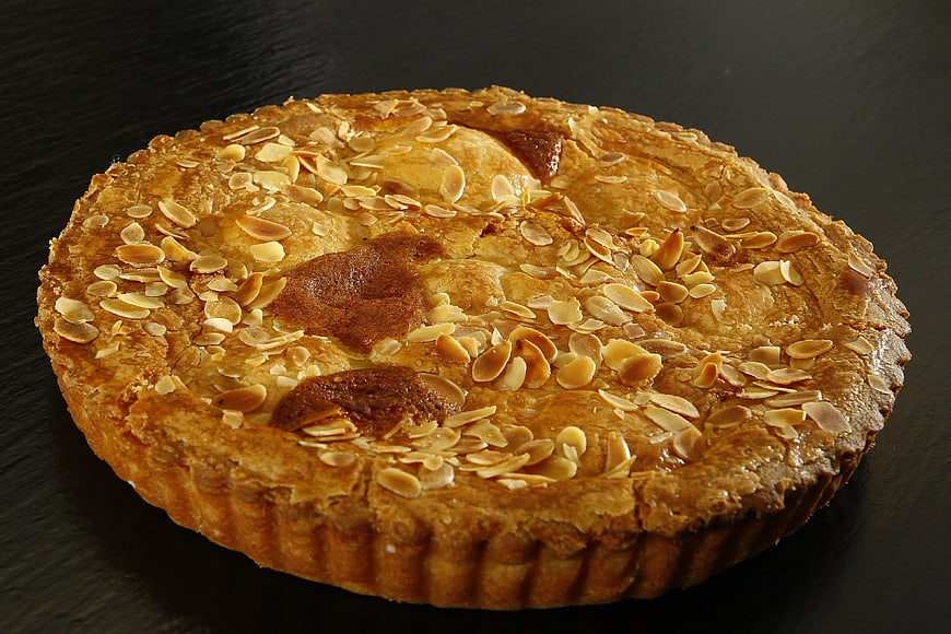 Golden almond tart on dark background