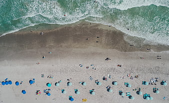 Aerial View of Beach with Blue Umbrellas and Ocean Waves