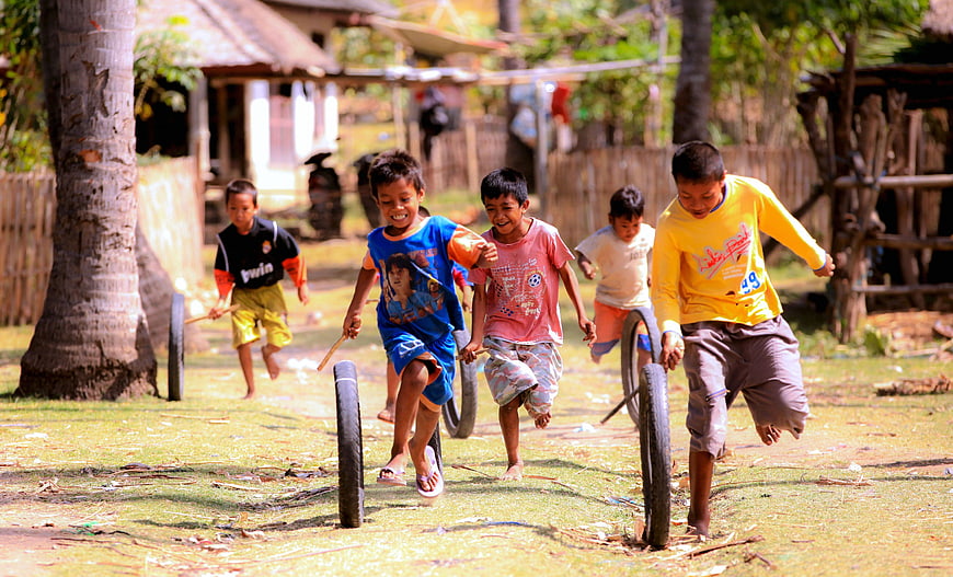 Happy children playing with bicycle wheels in a village