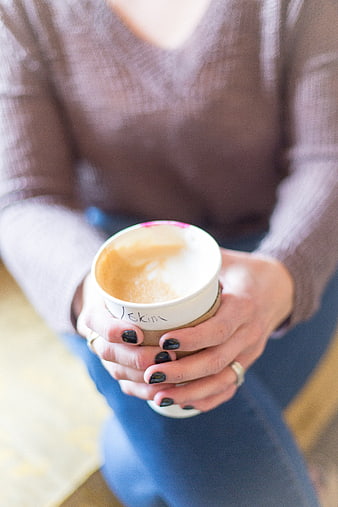 Woman holding warm coffee cup with latte art