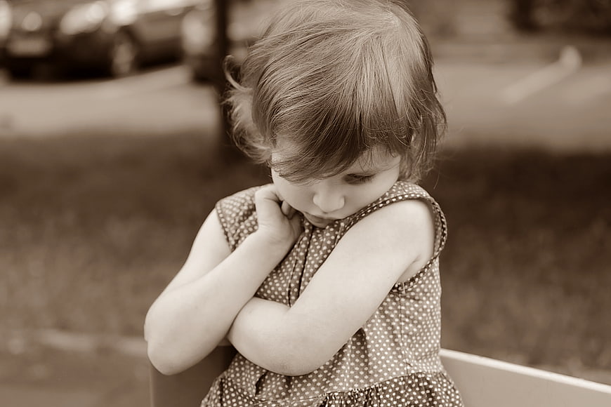 Sepia Portrait of Shy Little Girl Hiding Face in Polka Dot Dress