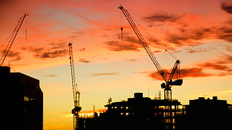 Construction Cranes Silhouette Against Vibrant Sunset Sky
