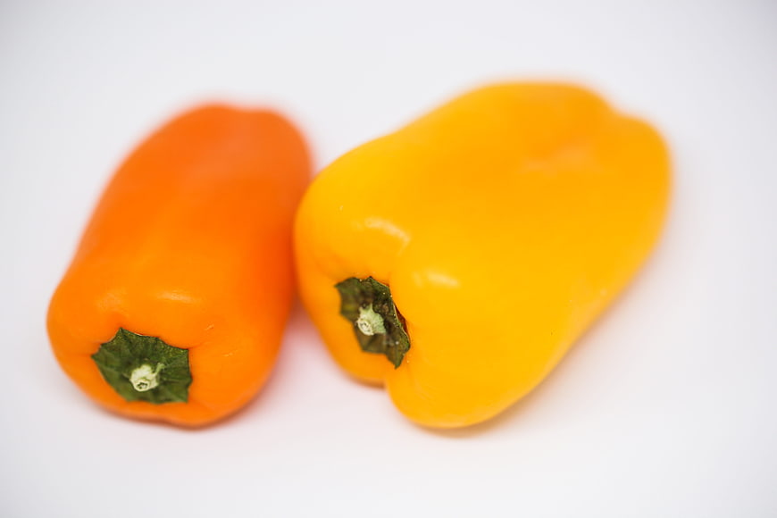 Fresh Orange and Yellow Bell Peppers on White Background