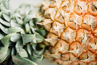 Close-up of textured pineapple skin and green leaves