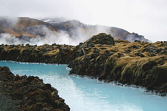 Misty Blue River Flowing Through Mossy Volcanic Rocks