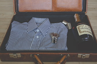 Vintage suitcase with striped shirt, watch, and Hennessy bottle