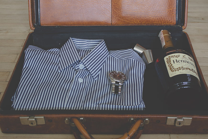 Vintage suitcase with striped shirt, watch, and Hennessy bottle