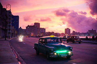 Vintage Green Taxi Driving on Havana Malecon at Sunset