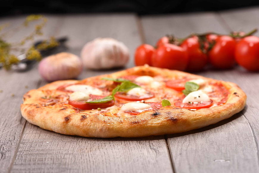 Fresh Margherita Pizza on Wooden Table with Tomatoes