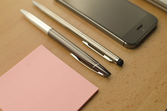 Office supplies with smartphone and pink sticky notes on wooden desk
