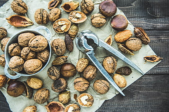 Flat lay of walnuts, chestnuts, and nutcracker on rustic wood