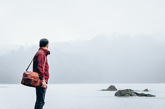 Man with Leather Bag Standing by Misty Lake