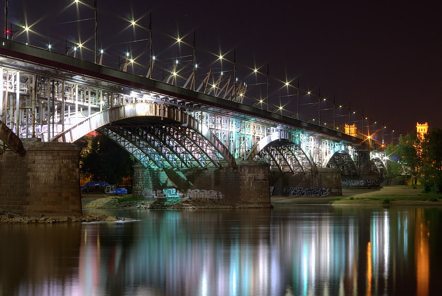 Illuminated Steel Arch Bridge at Night with Water Reflections