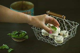 Hand picking mint macarons from wire basket