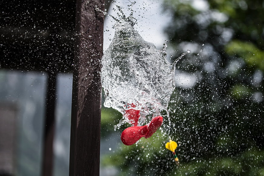 Red Water Balloon Bursting in Mid-Air Splash