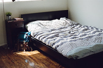Unmade bed with striped duvet in sunlit bedroom