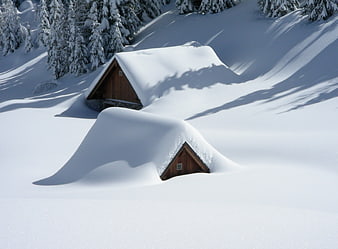 Snow-covered wooden mountain huts in winter alpine landscape