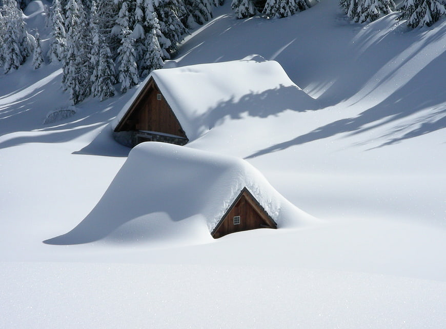Snow-covered wooden mountain huts in winter alpine landscape