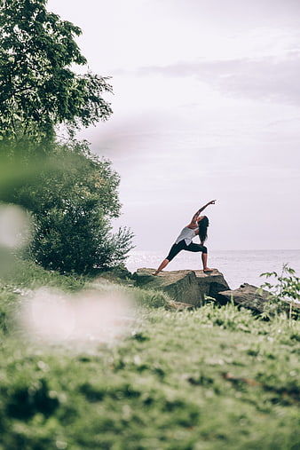 Woman Practicing Yoga on Rocks by the Ocean