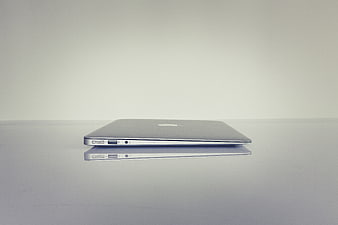 Closed Silver Laptop on White Reflective Surface