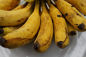 Close-up of ripe yellow bananas with brown spots on white plate