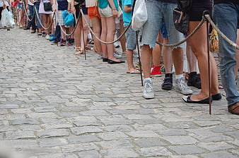 Crowd of people waiting in line on cobblestone street