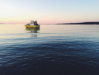 Yellow boat anchored on calm sea at sunset