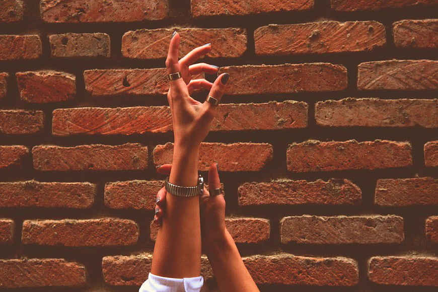 Hands with Rings and Watch Against Brick Wall