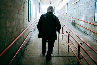 Senior man walking up ramp with cane
