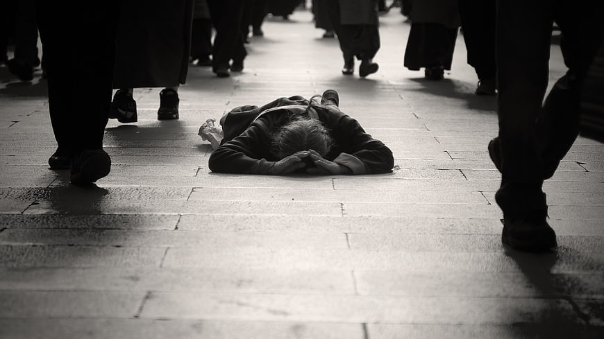 Prostrate Pilgrim Kneeling on Stone Street Amidst Crowds