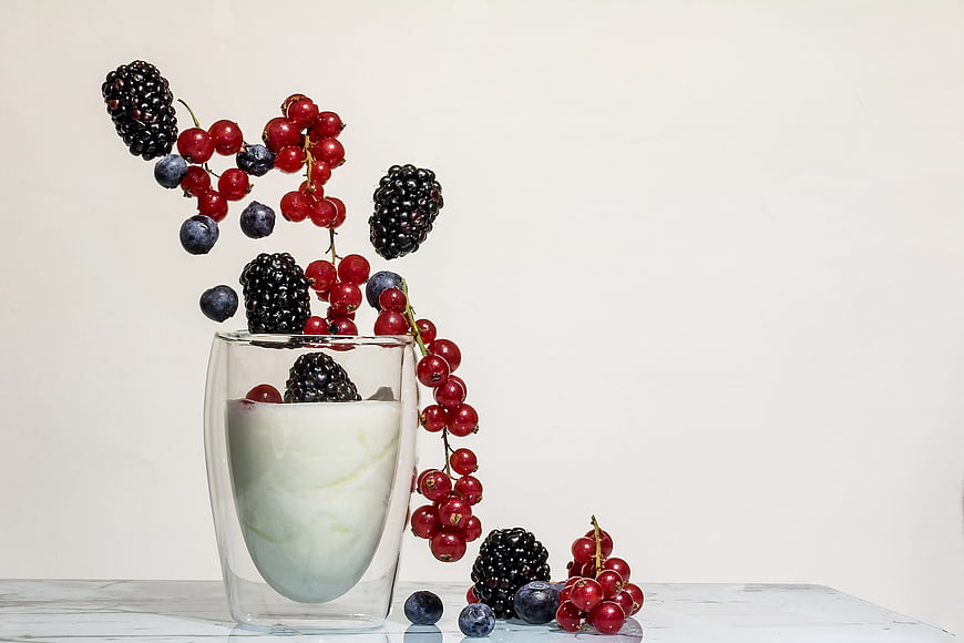 Frozen berries jumping out of yogurt glass