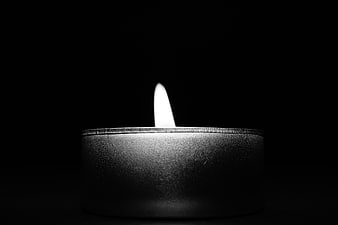 Black and white tea light candle flame on dark background