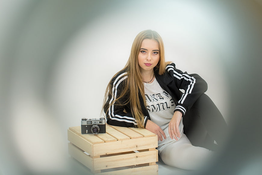 Young woman with vintage camera sitting on wooden crate