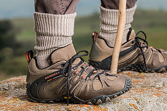 Close-up of brown Merrell hiking boots on rocky terrain
