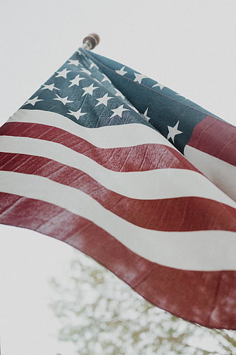 Close-up of American flag waving against overcast sky