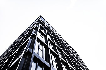 Low angle view of modern black skyscraper against white sky