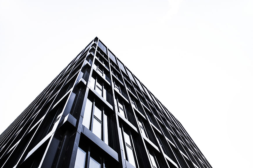 Low angle view of modern black skyscraper against white sky