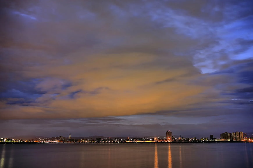 City Skyline at Dusk with Cloudy Sky and Water Reflections