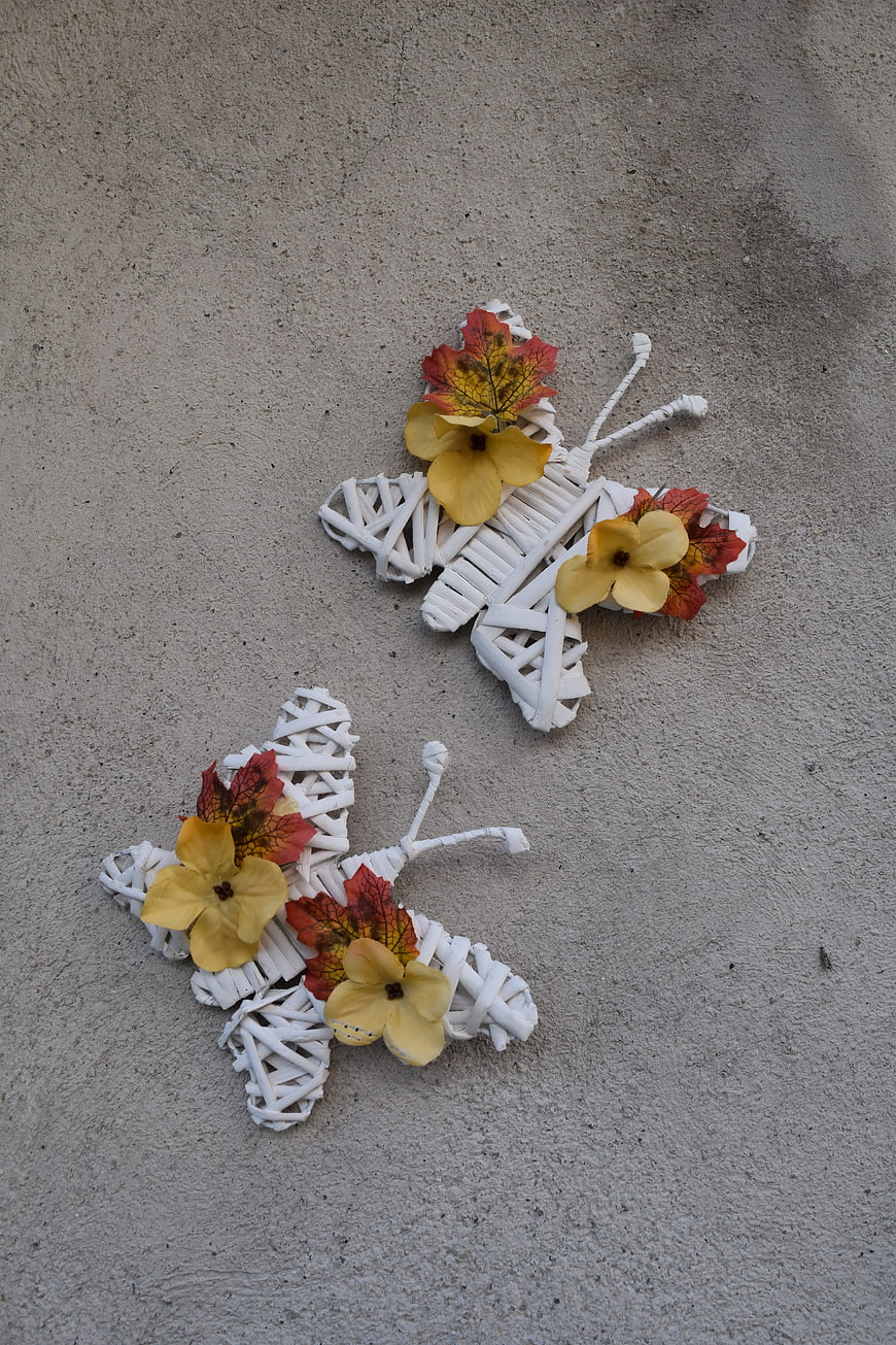 White Woven Butterfly Decorations with Yellow Flowers on Concrete