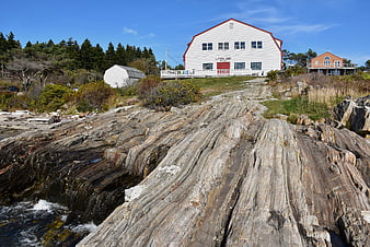 White barn on rocky Maine coast with ocean waves