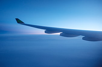 Airplane Wing Over Clouds at Sunset