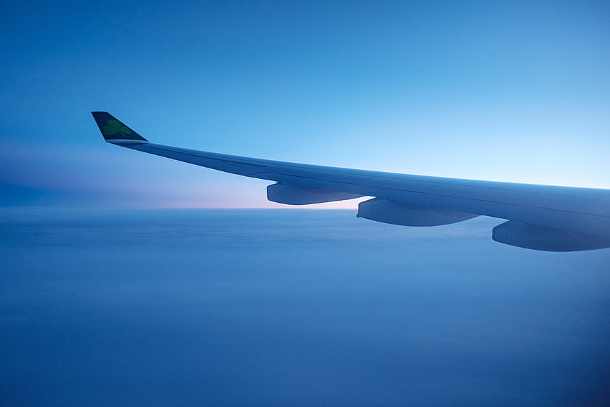 Airplane Wing Over Clouds at Sunset