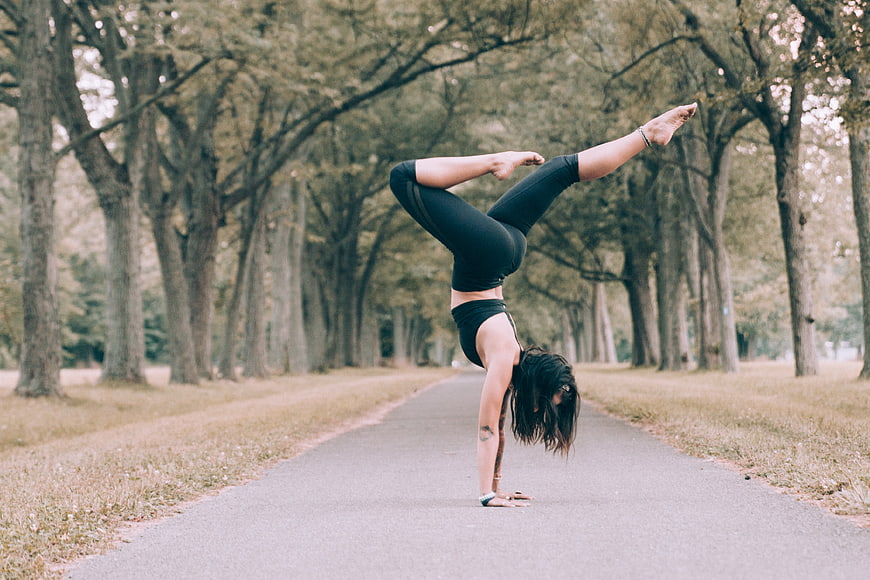 Woman Performing Handstand Yoga Pose on Forest Path
