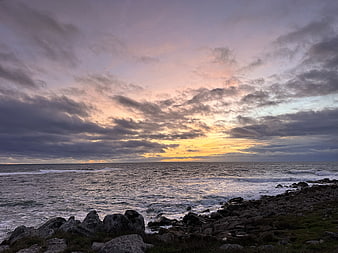 Dramatic sunset over rocky ocean coast with clouds