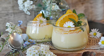 Creamy orange dessert in glass jars with flowers